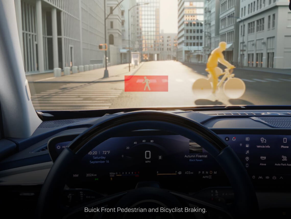 Driver cockpit view of a Buick Enclave HUD displaying a pedestrian warning system alert on a city street