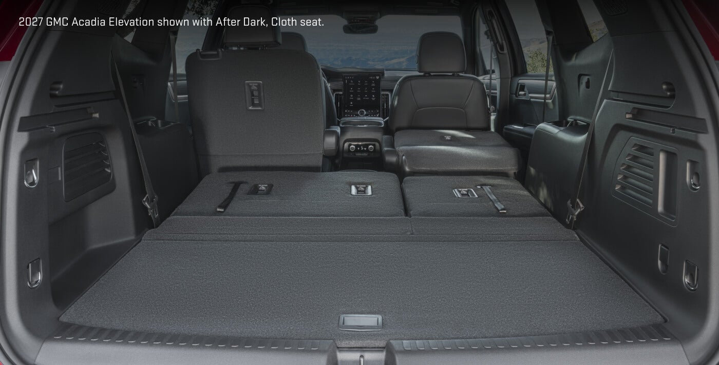 Interior rear cargo view of a 2027 GMC Acadia Elevation in After Dark Cloth with fold-flat second and third-row seating.
