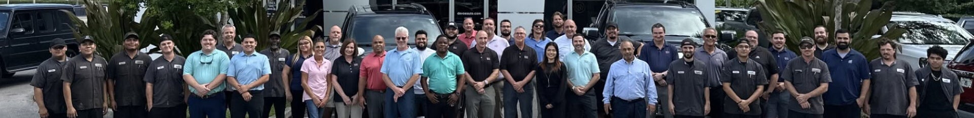 The Devoe Buick GMC team lined up outside the dealership on a sunny day.