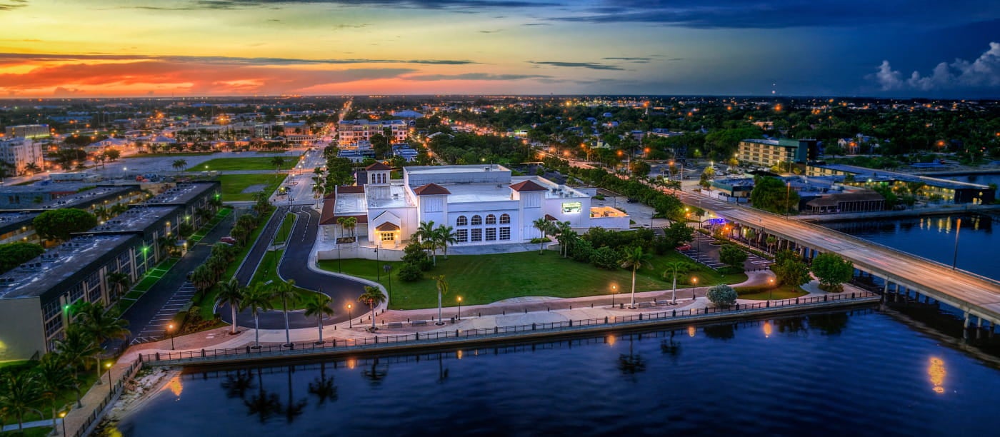 Aerial view of Punta Gorda at sunset, featuring a prominent white building near a calm waterfront.